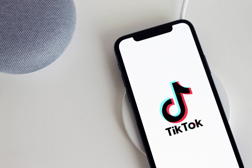 Teléfono móvil corporativo mostrando el lofo de tiktok sobre mesa diáfana de oficina.